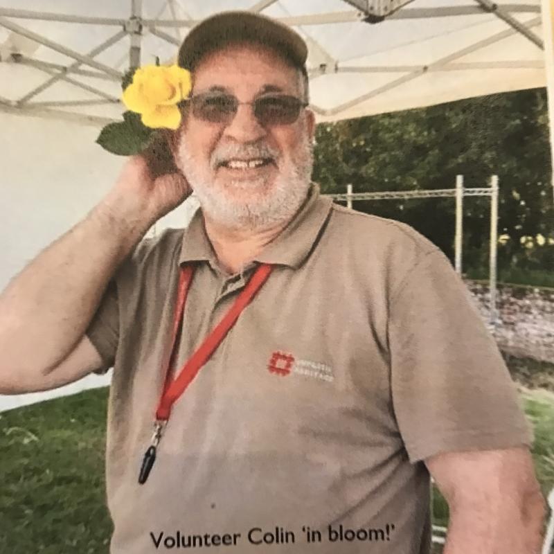 Colin in one of his many volunteering roles, posing with a yellow flower