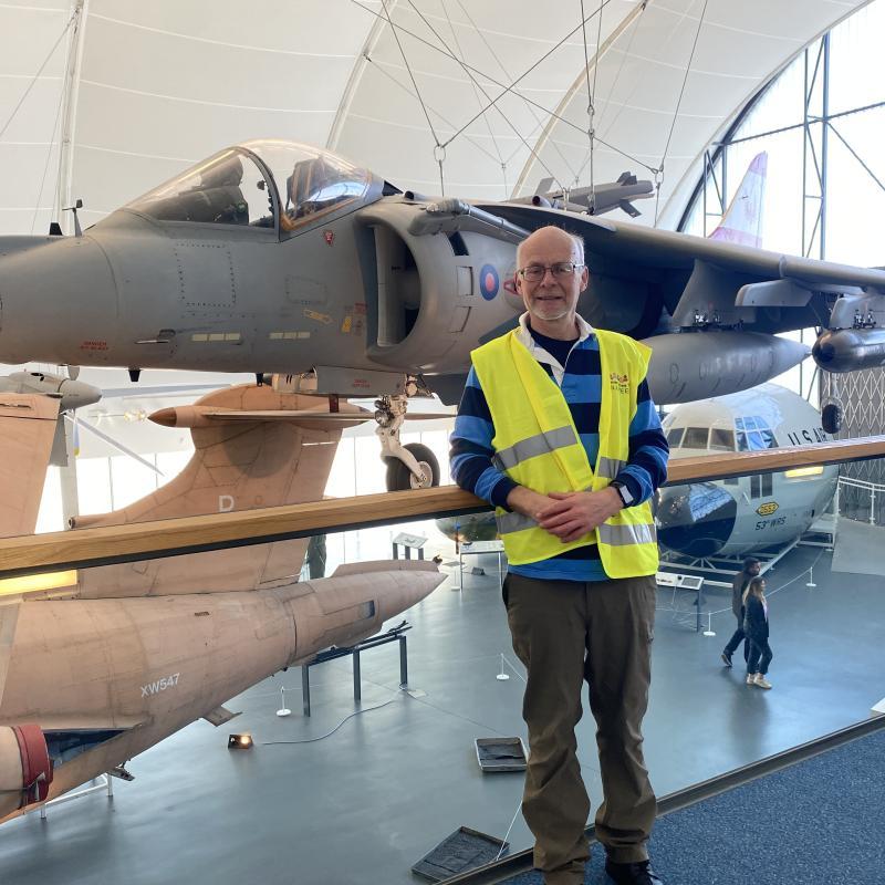 Community Transport Volunteer Robin posing beside a jet on one of the C1st day trips