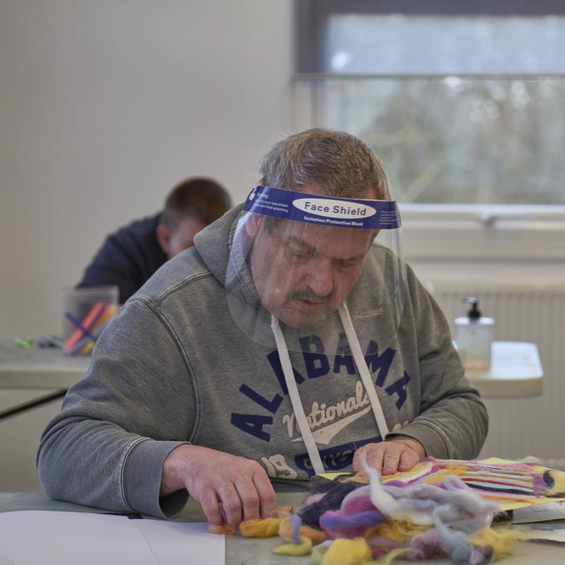 Man wearing a face shield working on a craft project